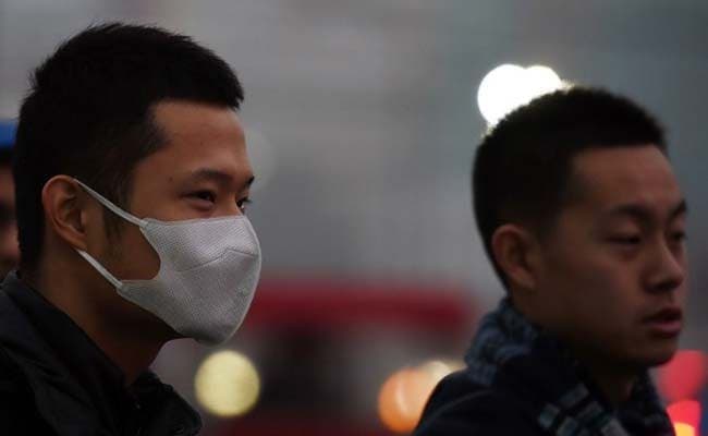 A man wears a mask as he crosses a road on a polluted day in Beijing on November 27, 2015. (Agence France-Presse)